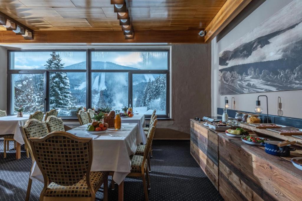 a dining room with a table and a large window at Wellness Hotel Šedý Vlk in Harrachov
