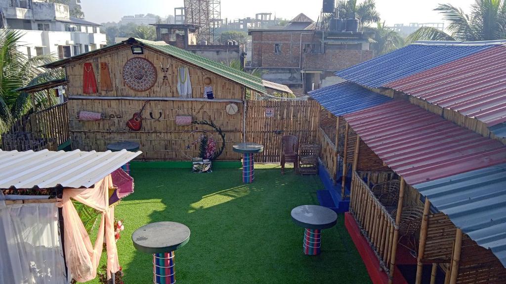 Un área al aire libre con taburetes en el césped de un edificio. en Tridhara HomeStay, en Guwahati
