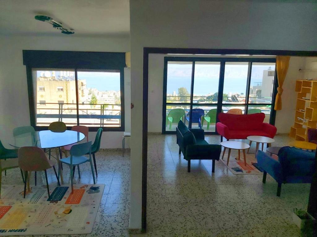 een woonkamer met stoelen, tafels en ramen bij turtle guesthouse- tiberias in Tiberias