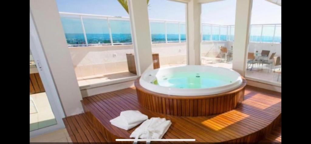 a large bath tub in a room with a large window at Flat hotel saint moritz in Brasilia