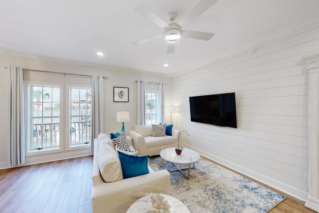 a living room with a couch and a tv on a wall at Village of South Walton EB210 in Rosemary Beach