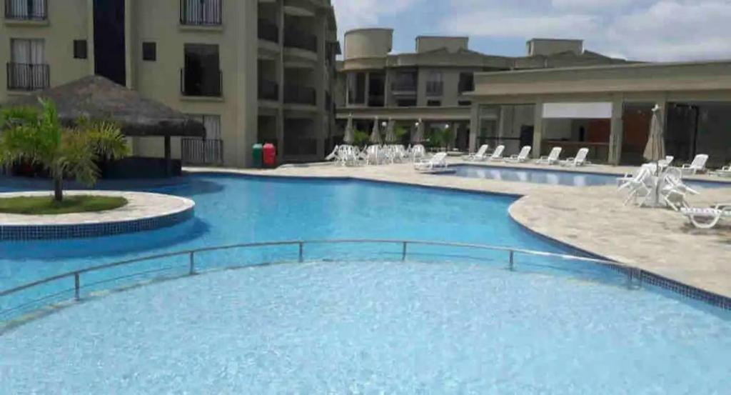 a large swimming pool in a resort with white chairs at Flat Quartier - Aldeia das Águas in Barra do Piraí