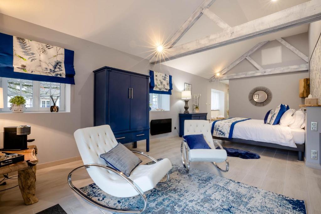 ein Schlafzimmer mit einem Bett und zwei weißen Stühlen in der Unterkunft Domaine De L´Oiseau in Gergy