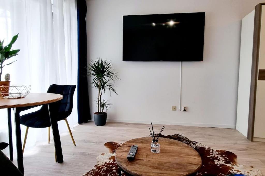 uma sala de estar com uma mesa e uma televisão na parede em Schönes Apartment in Erkrath, Nähe Düsseldorf em Erkrath