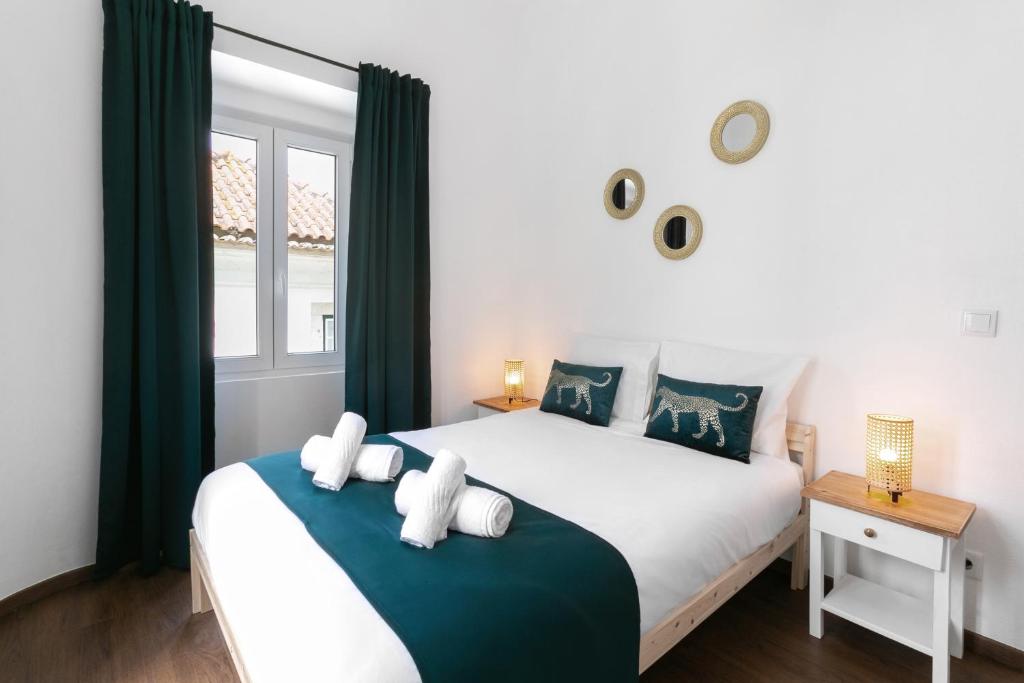 - une chambre avec un grand lit blanc et des rideaux verts dans l'établissement Old Town House, à Peniche