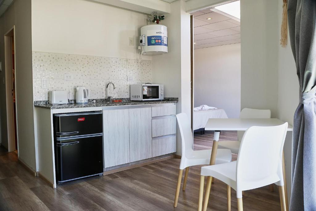 una pequeña cocina con mesa y sillas blancas en Aparts ALDEA DEL MONTAÑES en Mina Clavero
