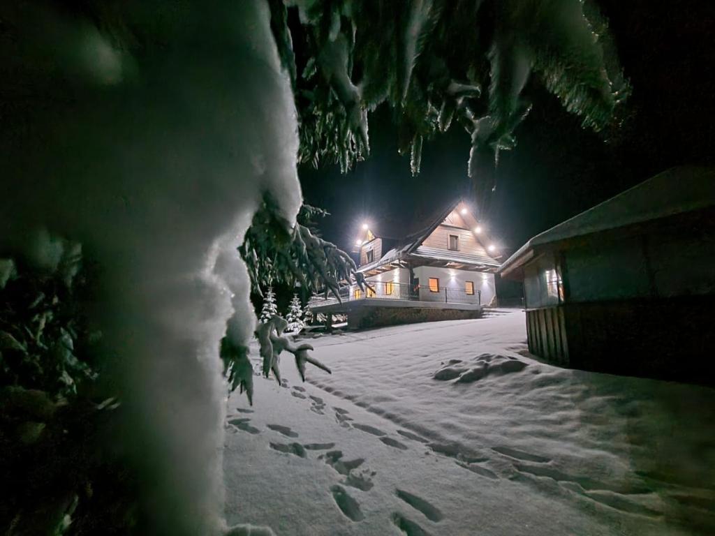a snow covered yard at night with a house at Willa pod Babią Górą in Zubrzyca Górna