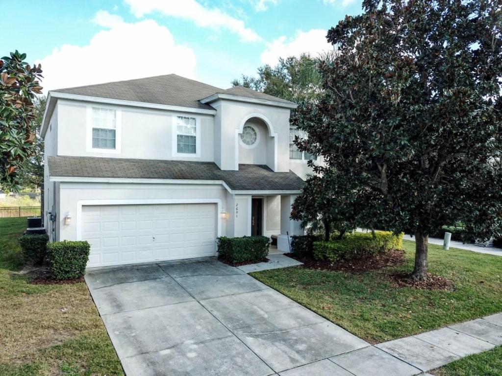 una casa blanca con un árbol y una entrada en This amazing 6 Bedroom property with a lake view villa, en Orlando