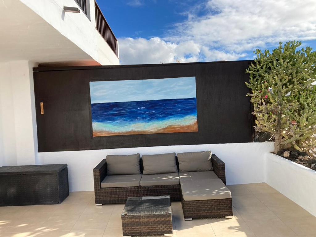 a patio with a couch and a painting on a wall at Apartamento Marina in Puerto del Carmen