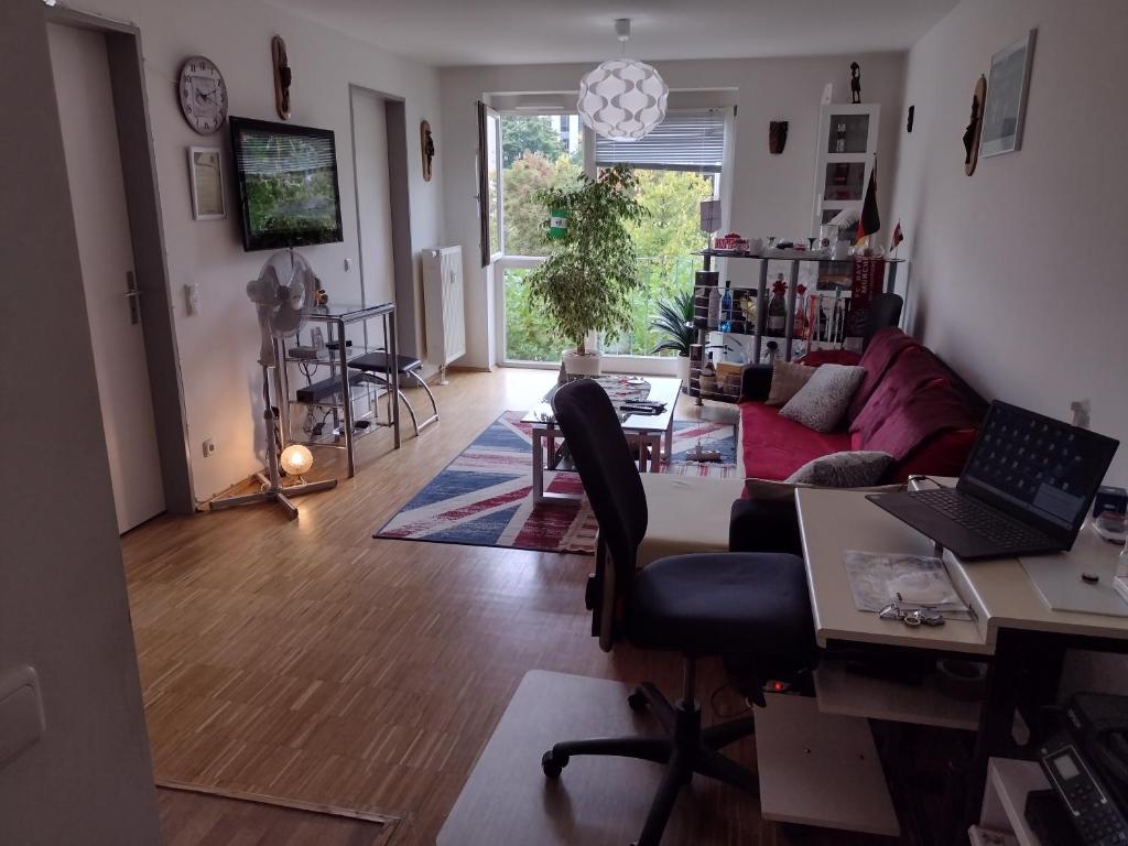 a living room with a couch and a desk with a laptop at 1 apartment with 2rooms in München in Munich
