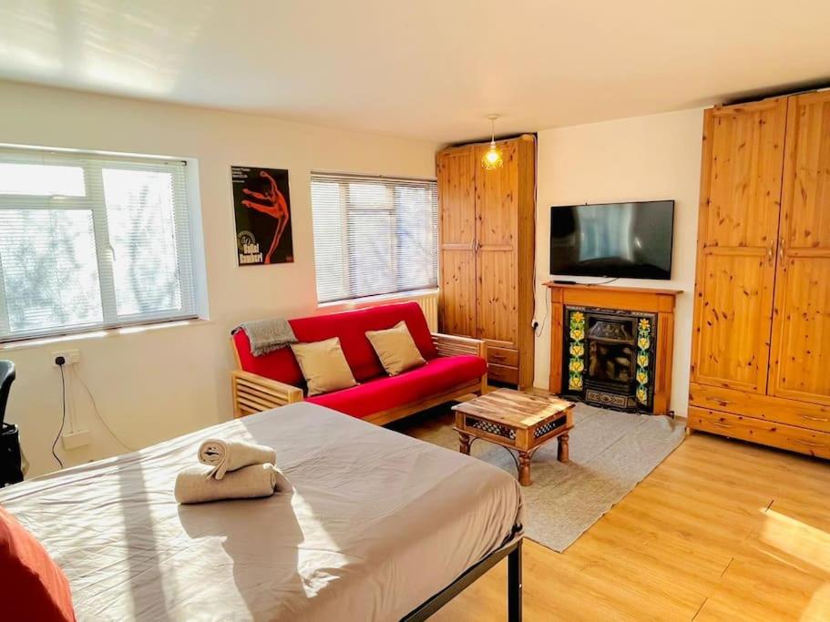 a living room with a red couch and a tv at St Albans Village Studios by DC London Rooms in London