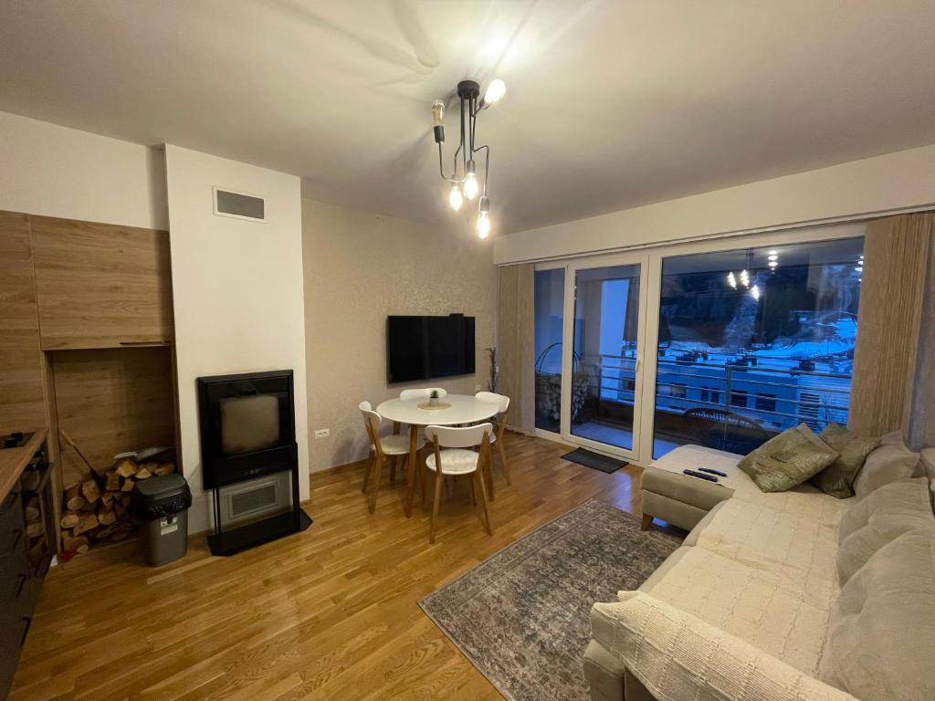 ein Wohnzimmer mit einem Sofa und einem Tisch in der Unterkunft Bjelašnica mountain view apartment in Bjelašnica