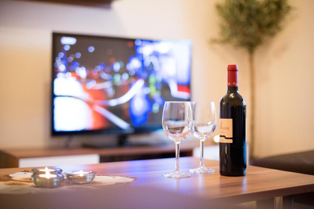 a bottle of wine and two wine glasses on a table at Harztour 1 Ferienwohnung in Quedlinburg