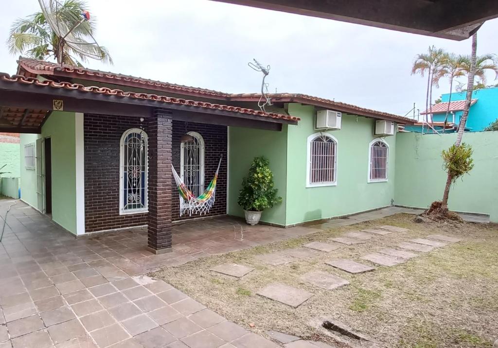 a green house with a tree in front of it at Casa Perto da Praia Caraguatatuba in Caraguatatuba