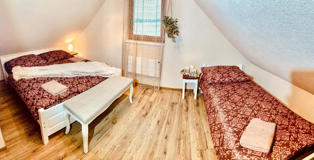 a bedroom with two beds and a table and a window at Romantické chalúpky Raj, Borievka a Čučoriedka in Hrabušice