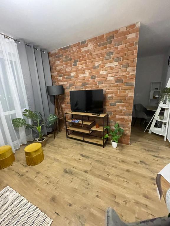 a living room with a brick fireplace and a television at NaturaApart bezpłatny parking in Ostrołęka