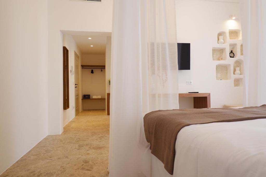 una camera da letto con pareti bianche, un letto e un corridoio di PALAZZO CAMERLENGO Suites Relax a Fasano