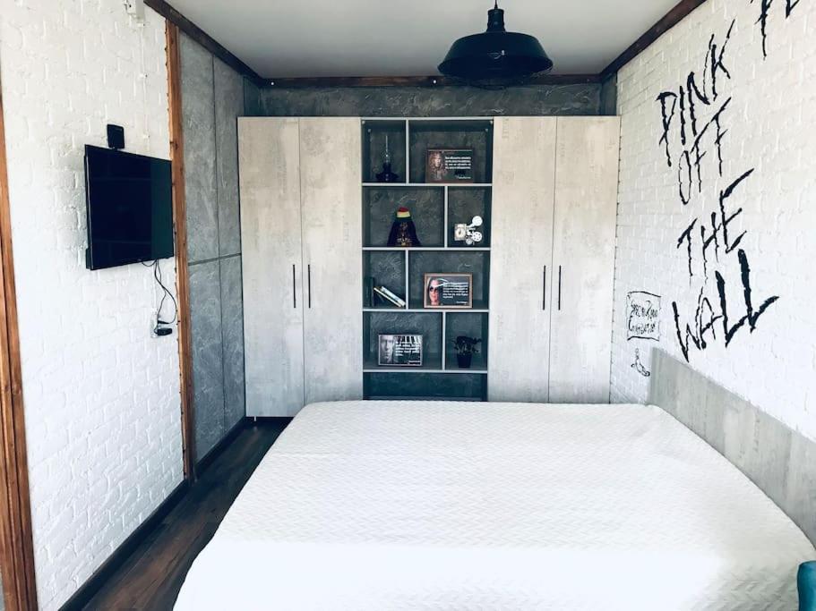 1 dormitorio con 1 cama blanca con graffiti en la pared en Квартира в стиле лофт для гостей Караганды en Karagandá