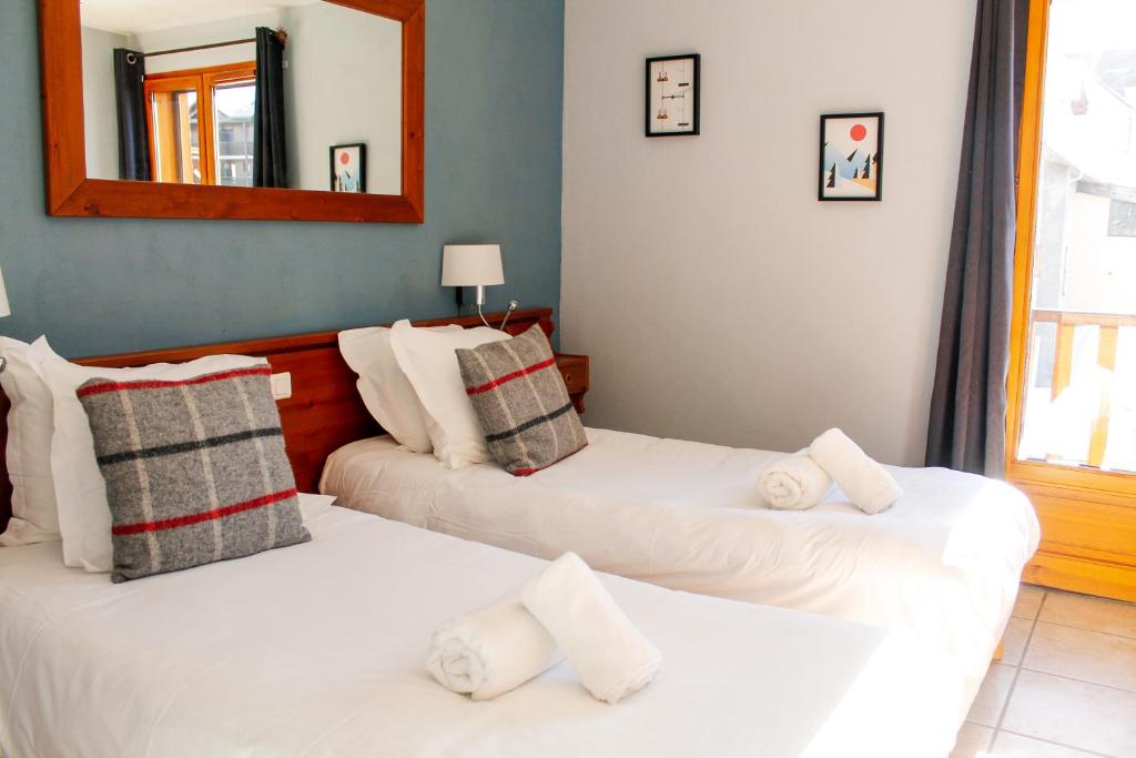 two white beds in a room with a mirror at Hôtel Mont Thabor Serre Chevalier in La Salle-les-Alpes