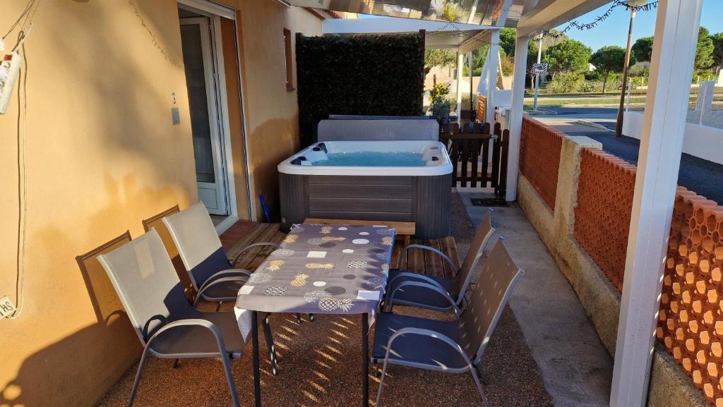 una mesa y sillas en un patio con bañera de hidromasaje en rêve méditerranéen, Le bonheur est dans ma maison, en Le Barcarès