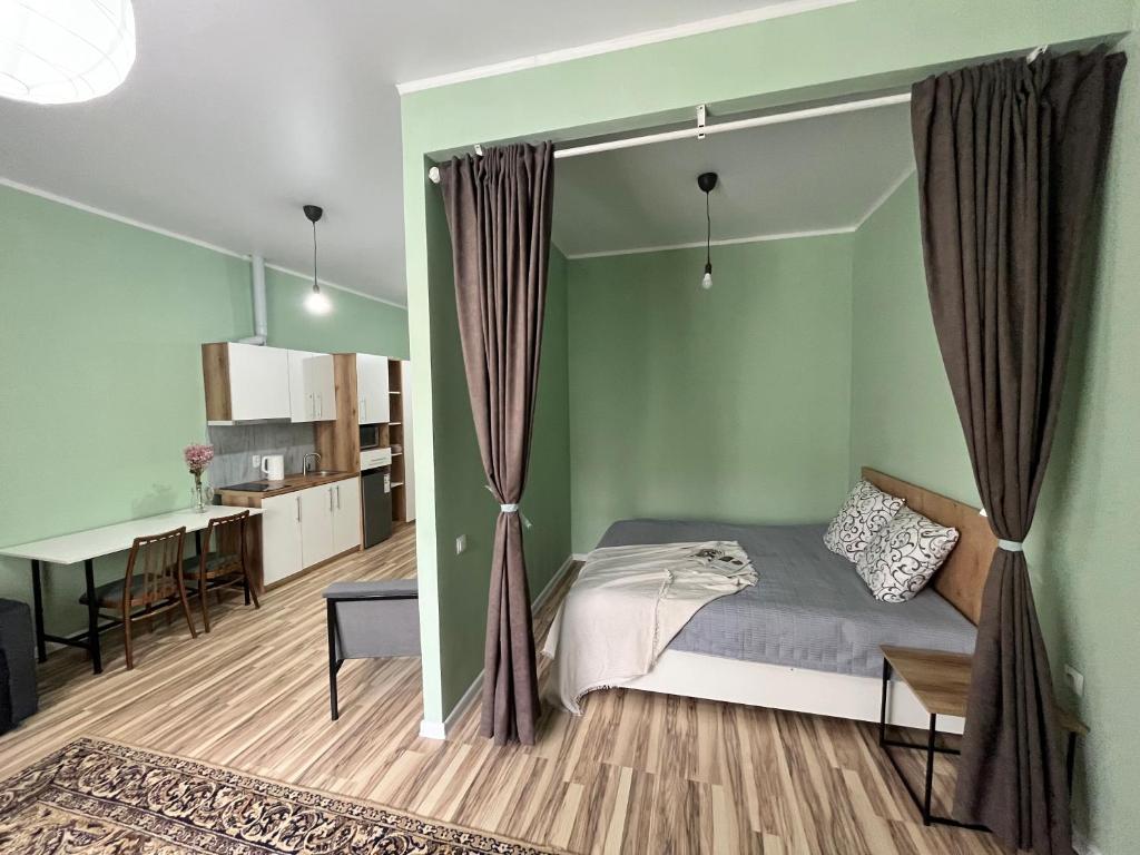 1 dormitorio con paredes verdes, 1 cama y 1 mesa en SN Apartments en Osh
