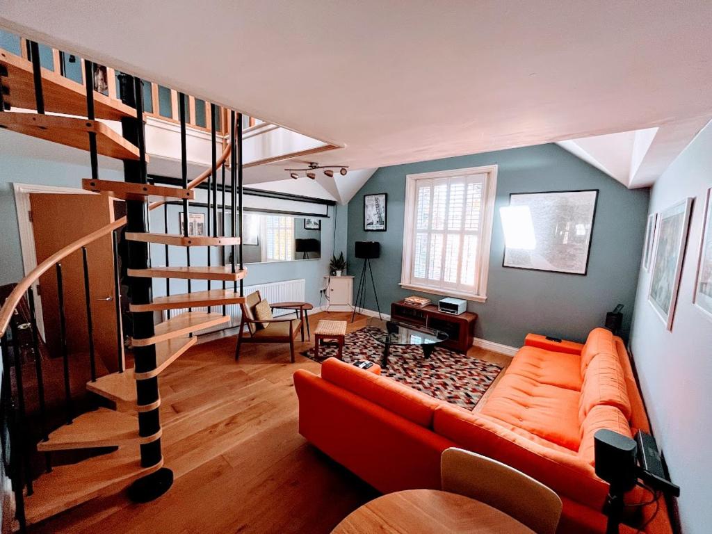 a living room with a couch and a spiral staircase at Retro penthouse flat, close to parks and centre in Liverpool