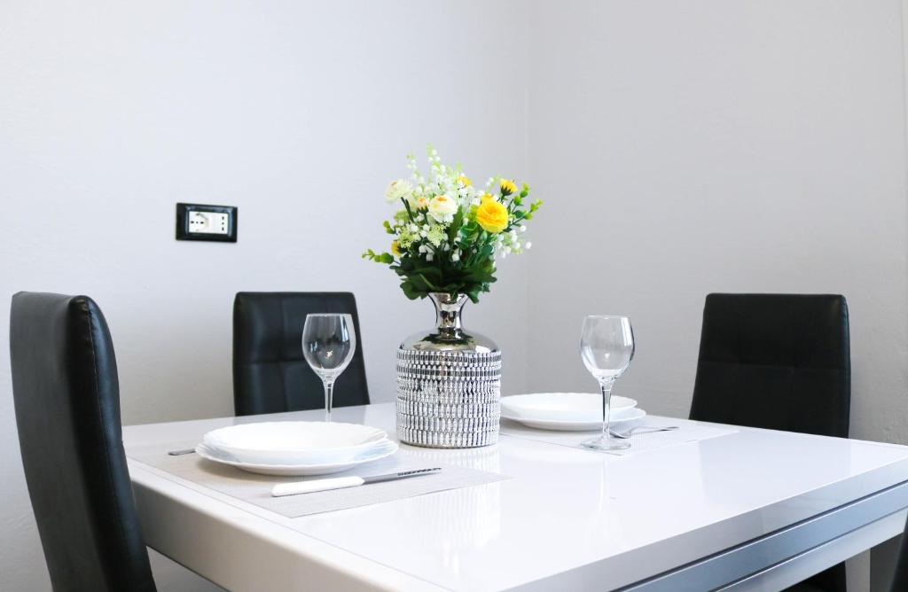 un tavolo bianco con un vaso di fiori e due bicchieri di H11 Bilocale Arma-Taggia - 1A a Taggia