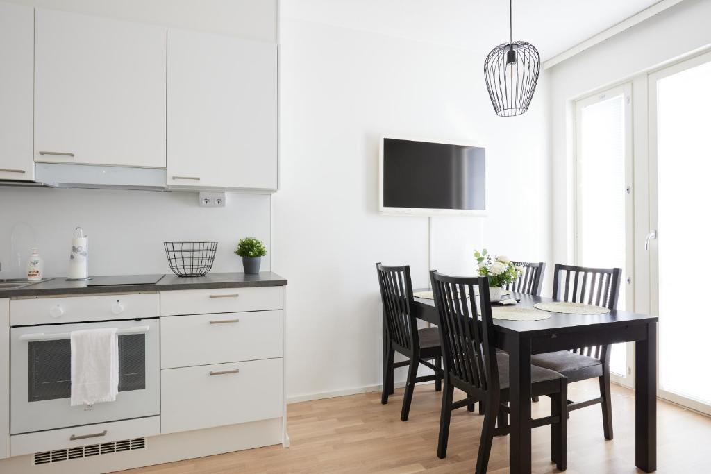 una cucina con tavolo, sedie e TV di New apartment w/WiFi & car park a Turku