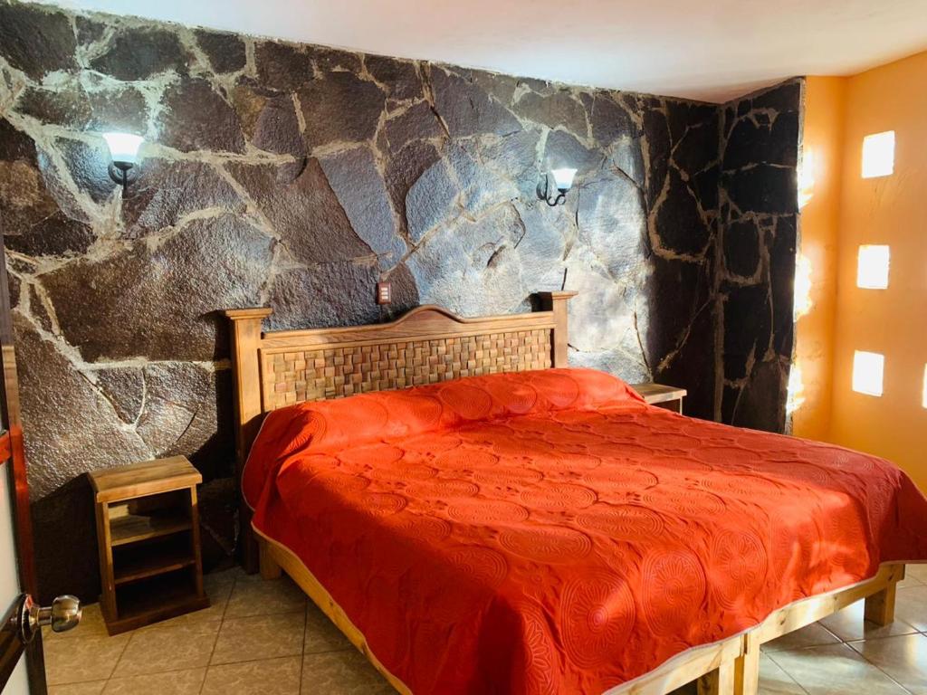 a bedroom with a stone wall with a bed at Hotel Posada Victor Antonio in Zacatlán