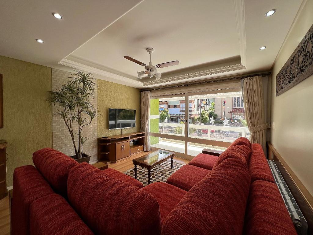 un gran sofá rojo en una sala de estar con TV en Morada da Montanha Centro by Achei Gramado, en Gramado