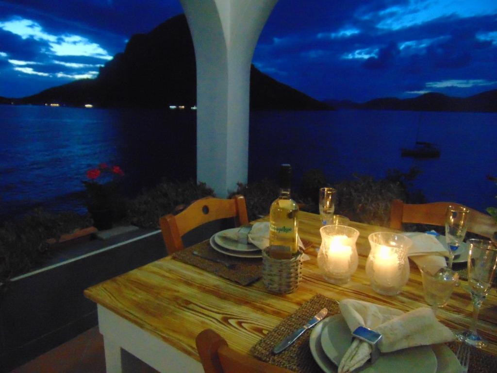 a table with candles and a table with a view of the water at Aegean Villa-On beach apartment! Ideal choice! in Masouri