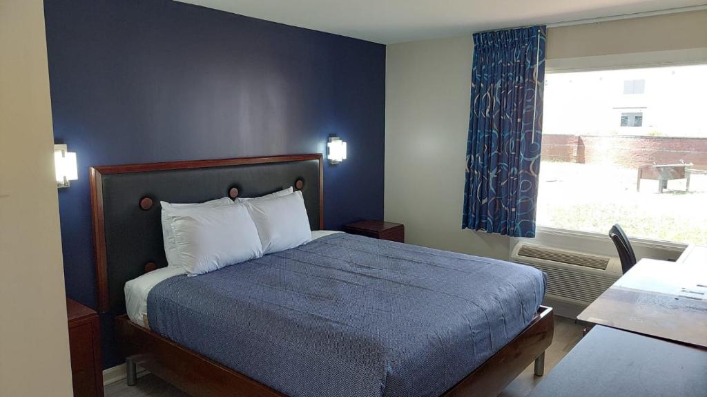 a blue bedroom with a bed and a window at Economy 7 Inn Hampton in Hampton