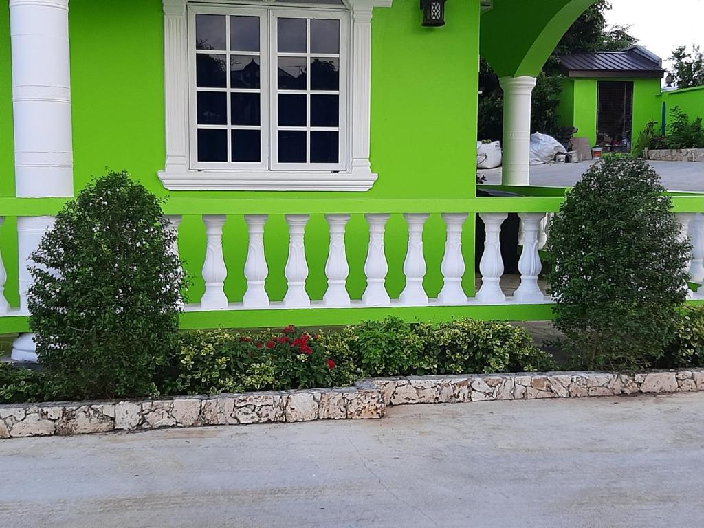 una casa verde con ventana y valla blanca en PESHERES INN & SPA, en Bon Accord