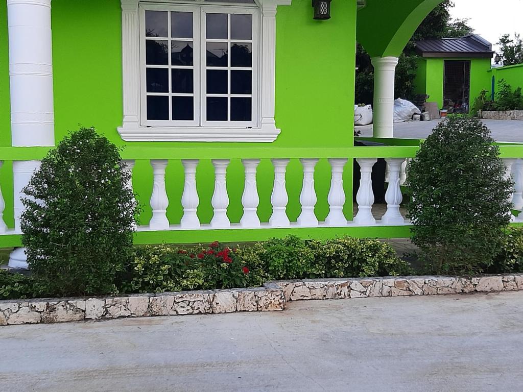 a green house with a window and a white fence at PESHERES INN & SPA in Bon Accord