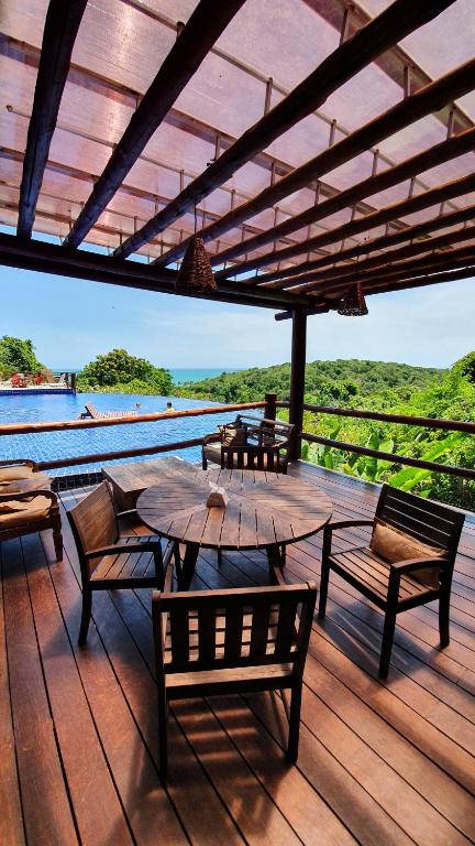 a wooden deck with a table and chairs and a pool at Villas do Pratagy Maceió in Maceió