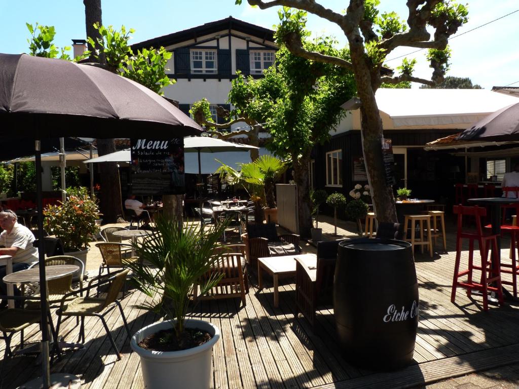 a patio with tables and chairs and a tree at Etche Ona in Pyla-sur-Mer