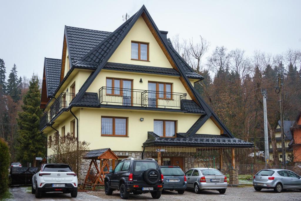 a large yellow house with a black roof at Budzowie in Białka Tatrzańska