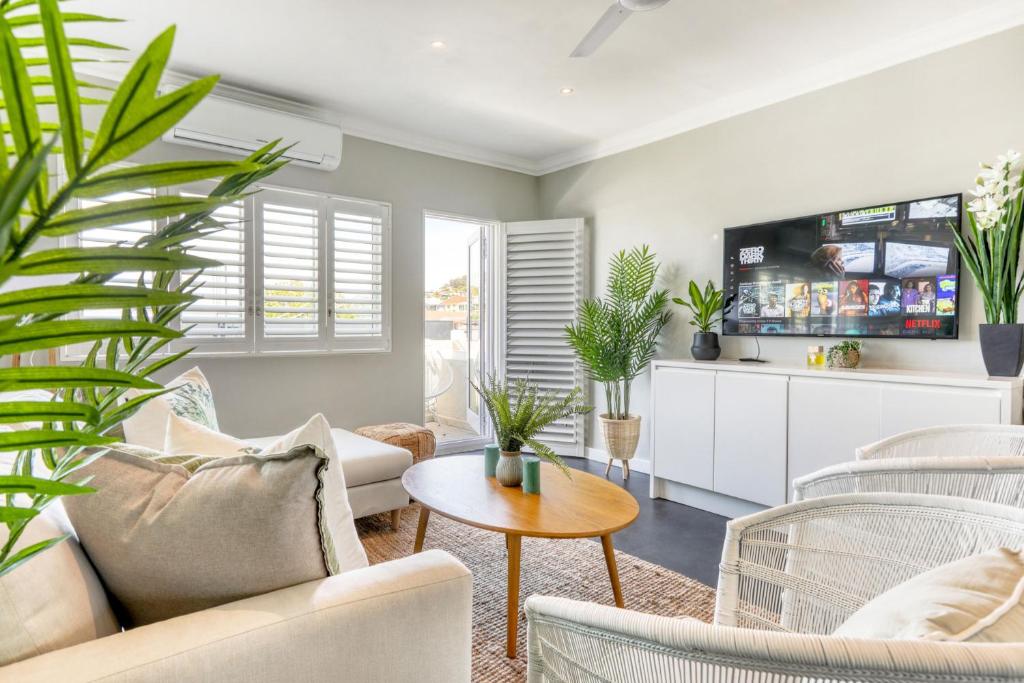 una sala de estar con muebles blancos y plantas en Backup-Powered Elegant Promenade Retreat, en Ciudad del Cabo