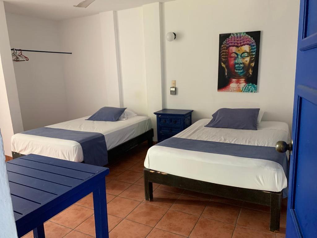 a room with two beds and a painting on the wall at MayFlower Hotel & Hostal in Puerto Escondido