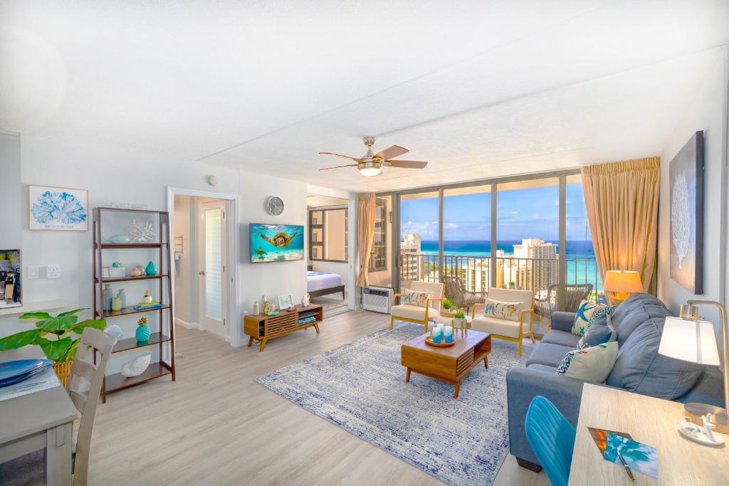 Waikiki Upscale 1 BR - Ocean Views - Parking في هونولولو: غرفة معيشة مع أريكة زرقاء ومحيط