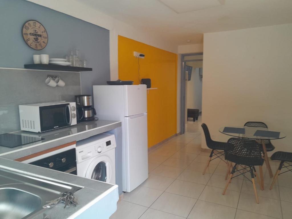 uma cozinha com um frigorífico branco e uma mesa com cadeiras em Cosy cannelle em Caiena