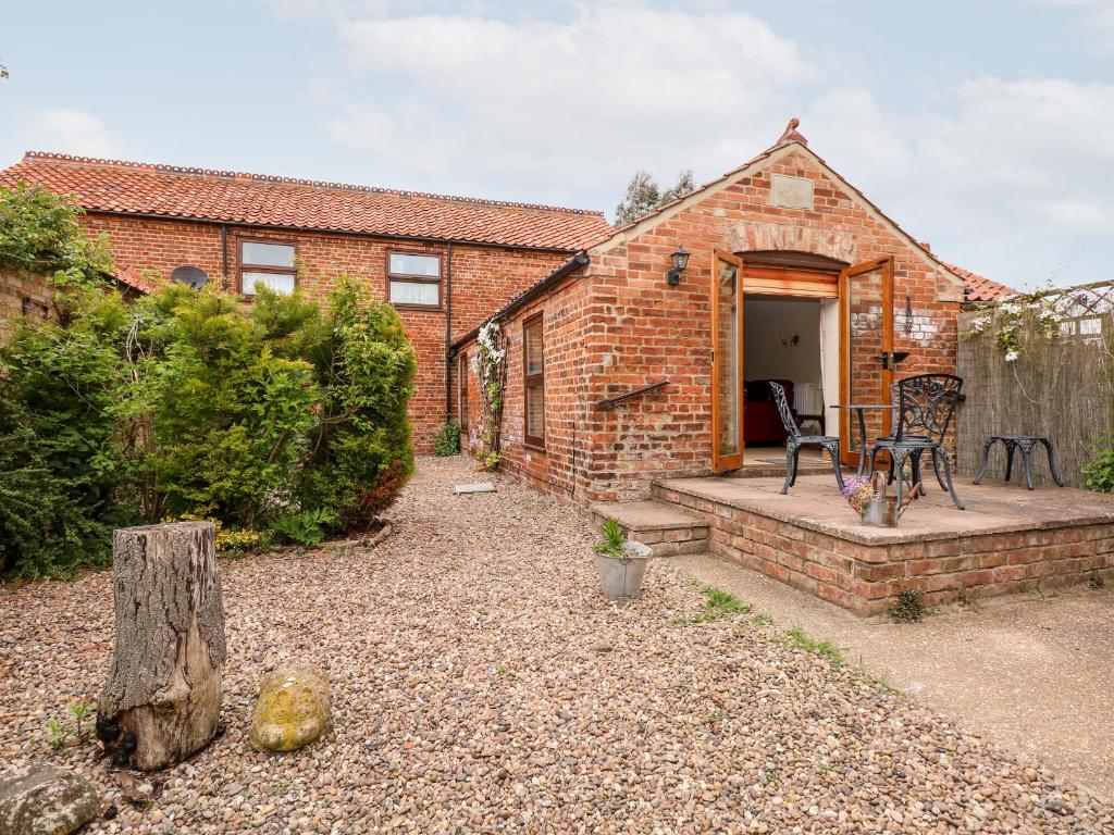 a brick house with a patio and a table and chairs at Clare's Cottage in Grainthorpe