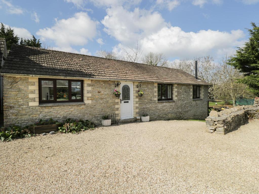 ein Backsteinhaus mit einer weißen Tür und einer Kieseinfahrt in der Unterkunft Orchard House Cottage in Malmesbury