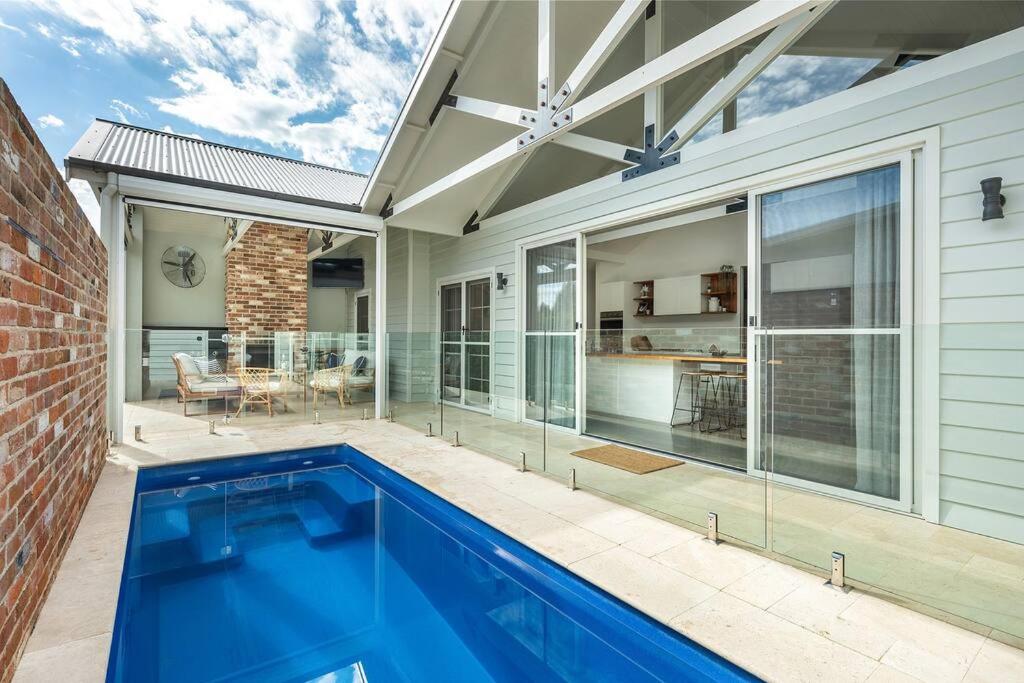 a swimming pool in front of a house at McG Mudgee a Hamptons inspired home in Mudgee
