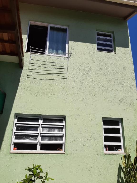 dos ventanas en el lateral de un edificio verde en Apartamento Atobá, en Florianópolis