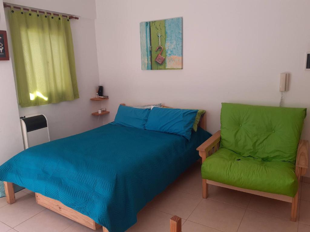 um quarto com uma cama e uma cadeira verde em DIVINO Colon 1 em Colón