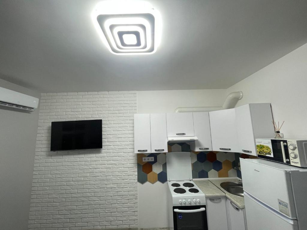 cocina con armarios blancos y TV en el techo en Parus Smart, en Leópolis