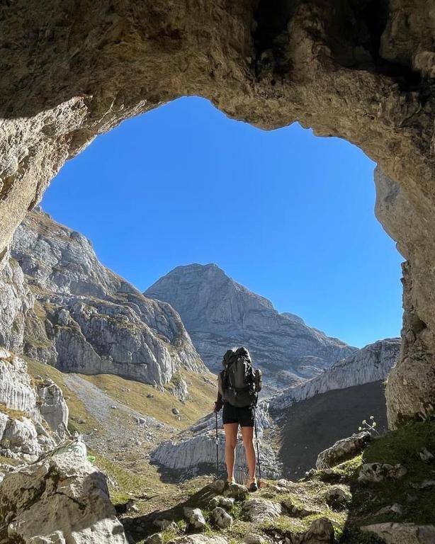 a person with a backpack walking through a rocky canyon at Dedushi Guesthouse &Wood cabins-Camping place in Gusinje