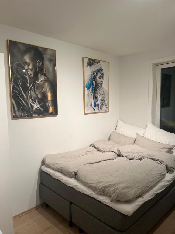 uma cama num quarto com três fotografias na parede em Nydelig leilighet med sentral beliggenhet. em Tønsberg