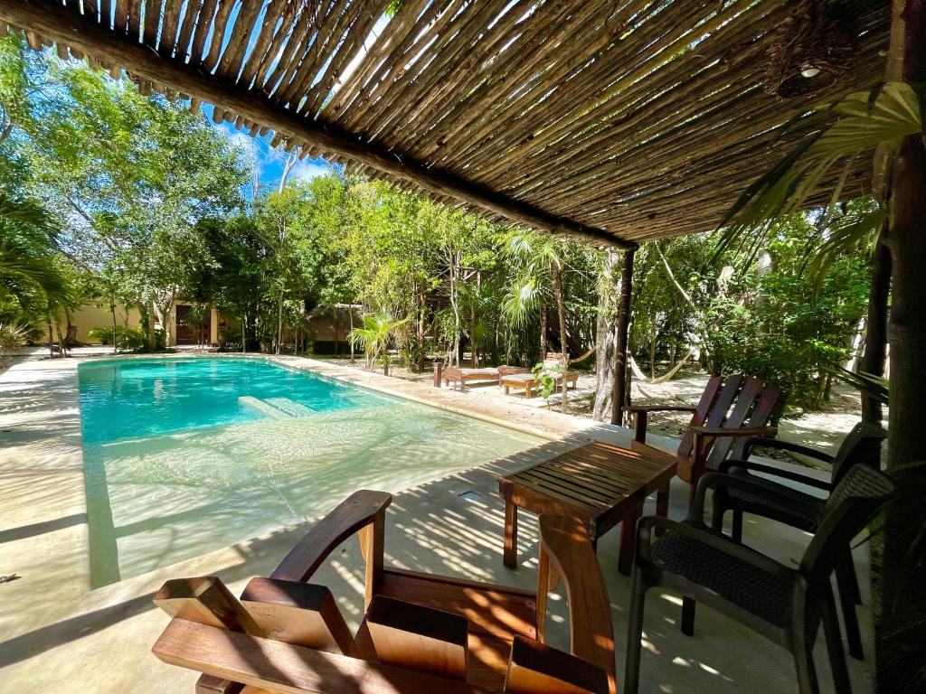 a patio with a table and chairs next to a swimming pool at Aldea Xaan Ha Tulum in Tulum
